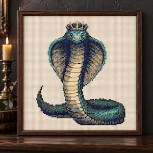 May include: A framed cross-stitch embroidery featuring a cobra snake wearing a crown. The snake is depicted in shades of teal, dark blue, and cream, set against a light beige fabric background within a dark brown wooden square frame.