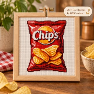 Puede incluir: Un patrón de punto de cruz en un bastidor de madera cuadrado que muestra una bolsa roja de patatas fritas con la palabra Chips impresa en blanco. El diseño incluye 76 x 103 puntadas y utiliza 14 colores DMC sobre tela Aida blanca.