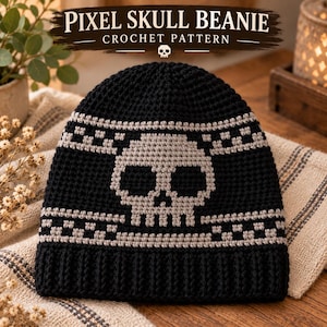 May include: A black crochet beanie featuring a gray pixelated skull design centered on the front, bordered by two horizontal rows of gray checkered patterns. The text PIXEL SKULL BEANIE CROCHET PATTERN is displayed in white above the beanie.