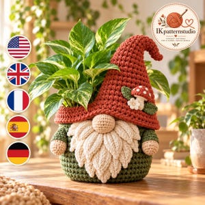 Puede incluir: Una funda de ganchillo para maceta con forma de gnomo, con un gorro alto y texturizado de color óxido, barba color crema y base verde oscuro. El gorro tiene un pequeño aplique de seta y flor. Una planta variegada verde y blanca está dentro.