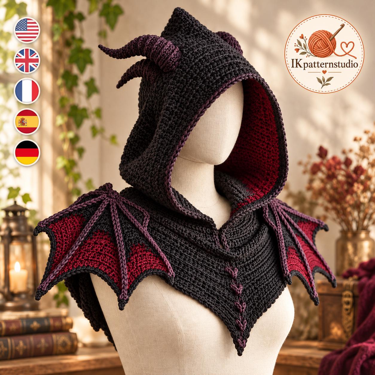 May include: A black and dark red crocheted hooded cowl featuring two prominent horns on top and two large dragon-like wings extending from the shoulders. The garment has a deep hood with a dark red interior lining and the text IKpatternstudio.