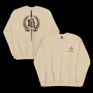 May include: A beige crewneck sweatshirt featuring a front graphic of a gold Jerusalem cross with the text "DEUS VULT" and a back graphic of a knight's helmet and sword encircled by a laurel wreath with a banner reading "EST. 1119".
