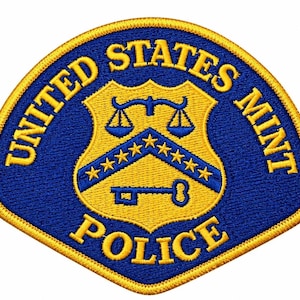Peut inclure: Un écusson brodé en forme de bouclier avec un fond bleu et une bordure jaune. Le texte UNITED STATES MINT POLICE est brodé en jaune. Le centre présente un bouclier jaune avec un chevron bleu, treize étoiles, une balance et une clé.