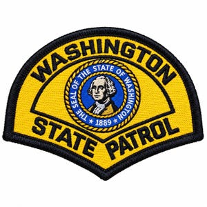 Könnte beinhalten: Ein halbkreisförmiger gestickter Aufnäher mit gelbem Hintergrund und schwarzem Rand. Der Text WASHINGTON STATE PATROL ist in Schwarz gestickt. In der Mitte befindet sich ein kreisförmiges Emblem mit einem Porträt von George Washington und dem Text THE SEAL OF THE STATE OF WASHINGTON 1889.
