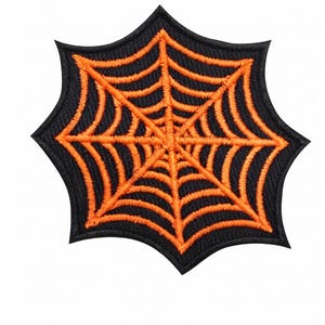 May include: A star-shaped embroidered patch featuring a black background with a vibrant orange spider web design. The patch has a thick black border and a textured surface created by dense stitching, forming a symmetrical web pattern.