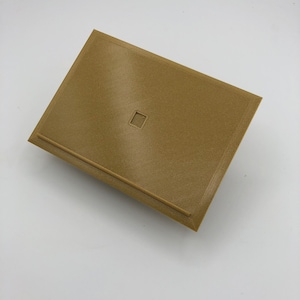 Peut inclure: Une boîte rectangulaire brune avec une ouverture carrée en haut. La boîte est faite d'un matériau texturé.