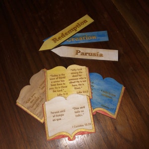May include: Four wooden bookmarks with gold and blue paint. Each bookmark features a different biblical passage and the word "Redemption", "Creation", "Parusia", or "God will be all in all".