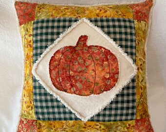 Almohada con apliques de calabaza y diseño de patchwork en batik y telas caseras en tonos naranja, verde y natural, con funda de mezclilla desgastada de 18"