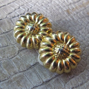 May include: A pair of gold-tone flower-shaped earrings with a textured surface.