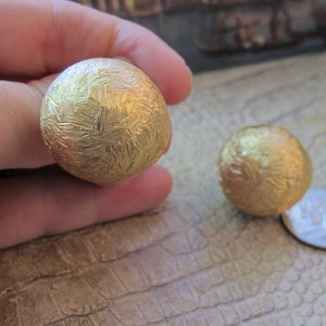 Orecchini pendenti di grandi dimensioni con sfera testurizzata e finitura dorata, firmati NAPIER, con chiusura a vite per un comfort ottimale, non forati.