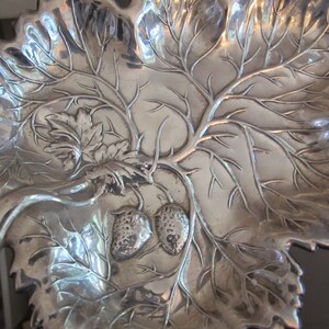 May include: A silver serving dish shaped like a leaf with a vine and two strawberries embossed on the surface.
