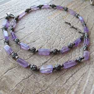 May include: A delicate necklace made with light purple amethyst beads and silver spacers. The necklace is layered and has a silver clasp.