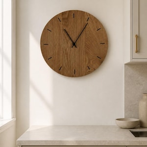 May include: A circular wall clock featuring a natural brown wood grain finish. The clock face has thin black hour markers and two slender black hands positioned at the center. The design is simple and round, displaying a clear wood texture throughout.