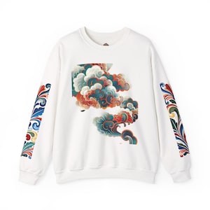 May include: A white crewneck sweatshirt featuring a central graphic of stylised swirling clouds in shades of teal, orange, and dark blue. The long sleeves are decorated with vertical bands of intricate, colourful floral scrollwork patterns.