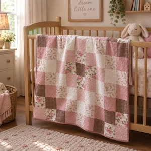 May include: A patchwork quilt featuring a repeating grid pattern of alternating squares. The design includes solid dusty pink squares, brown and white checkered squares, and white squares decorated with a small pink floral print pattern.