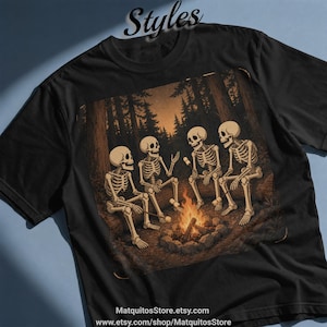May include: A black t-shirt featuring a graphic of four skeletons sitting around a campfire in a forest at night. The skeletons are holding sticks with marshmallows. The text "Styles" appears at the top, and "MatquitosStore.etsy.com" is at the bottom.