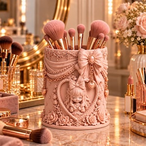 Puede incluir: Un porta brochas de maquillaje cilíndrico de color rosa con un relieve de una niña de pelo largo dentro de un marco de corazón, adornado con rosas esculpidas, patrones de tela drapeada, un lazo grande y dijes de corazón, lleno de brochas.