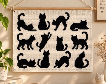 May include: A rectangular cream-colored crochet wall hanging featuring twelve black cat silhouettes in various poses. The textile is suspended from a wooden dowel with a white rope. The cats are arranged in a grid pattern across the fabric surface.