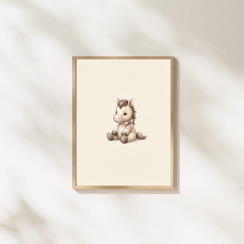 May include: A framed wall art print featuring a light brown cartoon horse sitting down. The horse has a cream-colored muzzle, a dark brown mane and tail, and a small light pink ribbon tied around its neck, all set against a plain off-white background.