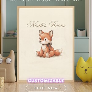 May include: A framed wall art print featuring a watercolour-style illustration of a seated orange and white fox with a dark brown ribbon around its neck. The text Noah's Room is printed in a script font above the fox on a cream-coloured background.