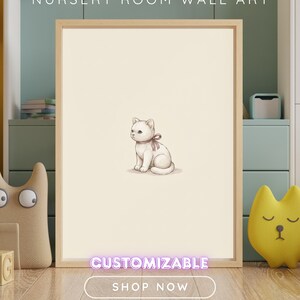 Puede incluir: Un cuadro de pared enmarcado que presenta la ilustraci&oacute;n de un gatito peque&ntilde;o de color claro con una cinta marr&oacute;n alrededor del cuello, centrado sobre un fondo crema. El texto NURSERY ROOM WALL ART, CUSTOMIZABLE y SHOP NOW es visible.