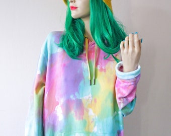 May include: A tie-dye hoodie with a yellow drawstring and a large front pocket. The hoodie is in shades of pink, yellow, blue, and green.