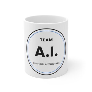 May include: A white ceramic mug featuring a circular graphic design. Inside the circle, the text reads TEAM A.I. ARTIFICIAL INTELLIGENCE in black lettering. The design is enclosed by a thick black border and a thin blue inner circular line.