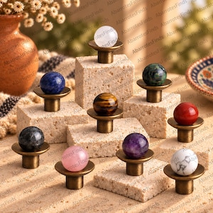 Puede incluir: Una colección de nueve pomos para armarios con remates esféricos de piedras preciosas en varios colores, incluyendo blanco, azul, verde, marrón, rojo, negro, rosa, morado y blanco con vetas grises, sobre bases circulares de latón antiguo.