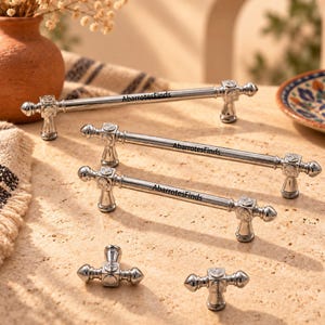 May include: A collection of silver-toned metal cabinet hardware, including three long bar pulls and two smaller T-shaped knobs. Each piece features square mounting bases with engraved floral details and the text AbarrotesFinds printed on them.