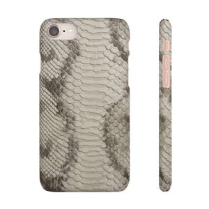 May include: A smartphone case featuring a light gray and beige snakeskin pattern. The back view shows a circular camera cutout at the top left, while the side view displays the slim profile with integrated buttons in a matching light tone.