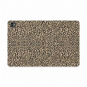 Peut inclure: Une coque de tablette rectangulaire présentant un motif léopard répétitif dans des tons de beige, marron et noir. La coque possède une surface lisse et une découpe circulaire pour l'appareil photo située dans le coin supérieur gauche.