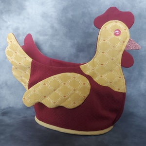 May include: A red and gold fabric chicken-shaped basket with a decorative pattern. The basket is made of a soft, plush fabric and has a large opening at the top.