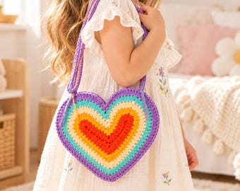 May include: A heart-shaped crochet bag featuring concentric layers of purple, turquoise, yellow, orange, and red yarn. The bag includes a matching purple crochet strap and is constructed with a textured, hand-stitched yarn pattern throughout.