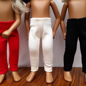 Peut inclure: Trois paires de leggings pour poupée en rouge, blanc et noir.