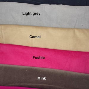 Pu&ograve; includere: Una collezione di sette strisce di tessuto a coste impilate in vari colori, etichettate con il testo: Scarlet, Navy, Light grey, Camel, Fushia, Mink e Magenta. Ogni striscia di tessuto presenta una distinta trama a coste e tinta unita.