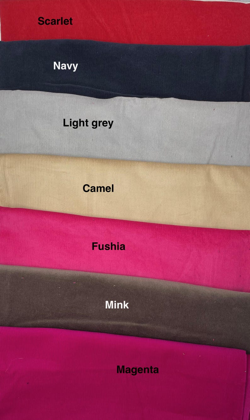 Pu&ograve; includere: Una collezione di sette strisce di tessuto a coste impilate in vari colori, etichettate con il testo: Scarlet, Navy, Light grey, Camel, Fushia, Mink e Magenta. Ogni striscia di tessuto presenta una distinta trama a coste e tinta unita.