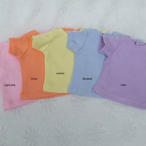 Può includere: Cinque magliette semplici in diversi colori: rosa chiaro, corallo, limone, campanula blu e lilla.