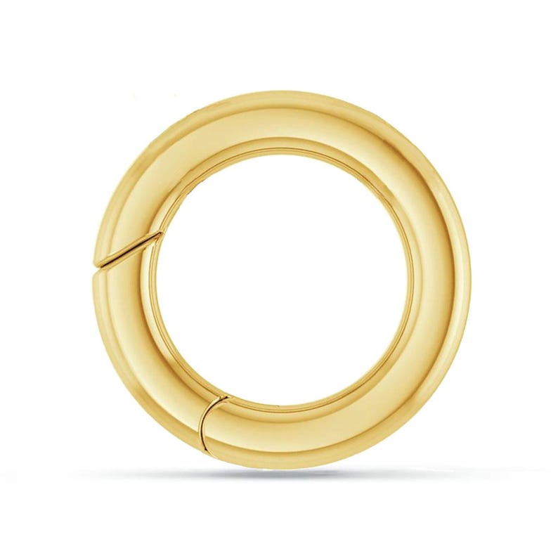 Puede incluir: Un anillo de metal dorado con una superficie lisa y redondeada. El anillo est&aacute; abierto y tiene un cierre con bisagra.