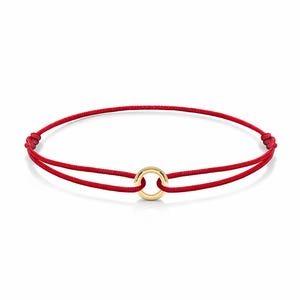May include: A red cord bracelet with a gold-colored circular charm. The bracelet is knotted at both ends. The gold charm is centered on the red cord.