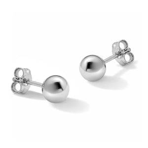 May include: A pair of shiny, silver ball stud earrings. Each earring features a smooth, spherical design and a post with a butterfly backing. The earrings are displayed on a white background, highlighting their reflective surface.