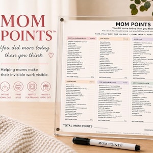 Könnte beinhalten: Ein transparenter Acrylrahmen mit einer Mom Points-Checkliste, die Kategorien wie Keeping Humans Alive, The House, Mom CEO, Taking Care of Me, Parenting, The Invisible Load und Emotional Labor enthält, zusammen mit einem schwarzen Whiteboard-Marker.