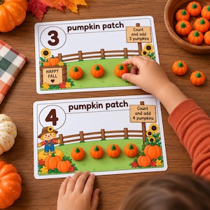 May include: Two rectangular educational activity cards labeled pumpkin patch with the numbers 3 and 4. Each card features a wooden fence, sunflowers, and text instructions to count and add pumpkins, accompanied by small orange pumpkin figurines.