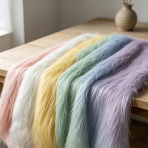 May include: A multi-coloured faux fur fabric runner featuring a gradient of pastel shades including soft pink, white, pale yellow, mint green, light blue, and lavender. The long-pile material has a shaggy texture and is draped in parallel folds.