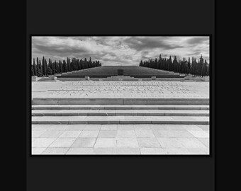 Un monument aux morts en noir et blanc, des marches pyramidales entre des cyprès s'élevant vers le ciel. Téléchargement numérique.