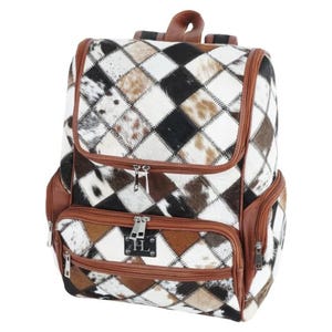 May include: A backpack featuring a diamond-patterned patchwork design made of white, black, and brown cowhide fur. The bag includes brown leather trim, multiple zippered compartments, and a rectangular metal logo plate with the letters HL on the front.