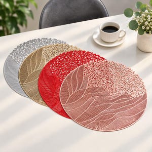 Peut inclure: Un ensemble de quatre sets de table circulaires en argent, or, rouge et or rose. Chaque set présente un design découpé au laser avec une section solide affichant des lignes courbes fines et une section contrastée au motif ajouré complexe.
