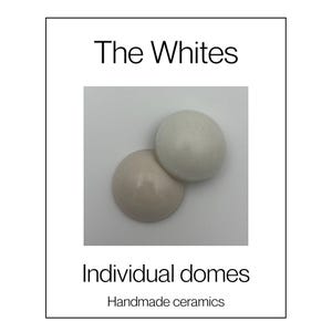 May include: Two ceramic domes, one in a matte off-white and one in a glossy light beige, are displayed against a white background. The text "The Whites", "Individual domes", and "Handmade ceramics" is printed in black on the white border.