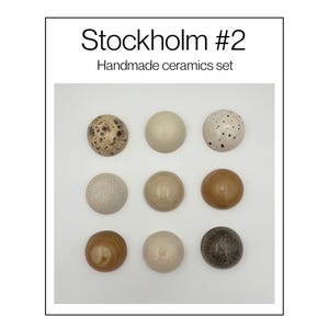 Może przedstawiać: Zestaw dziewięciu okrągłych elementów ceramicznych ułożonych w siatkę trzy na trzy, z napisem Stockholm #2 Handmade ceramics set. Elementy mają różne wykończenia, w tym nakrapiane, jednolite beżowe, brązowe i ciemnoszare odcienie o gładkich powierzchniach.