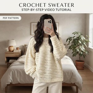Può includere: Un maglione all'uncinetto color crema a maniche lunghe con una consistenza a coste e uno scollo rotondo. L'immagine include il testo CROCHET SWEATER STEP-BY-STEP VIDEO TUTORIAL e PDF PATTERN. Il maglione presenta una vestibilità ampia e punti orizzontali.