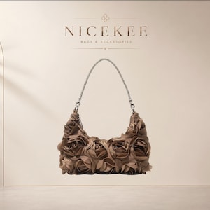 Puede incluir: Un bolso tipo hobo de color topo adornado con aplicaciones de rosas de tela superpuestas que cubren todo el exterior. El bolso cuenta con una sola correa de hombro metálica de tono plateado sujeta con mosquetones. El texto NICEKEE BAGS & ACCESSORIES es visible.